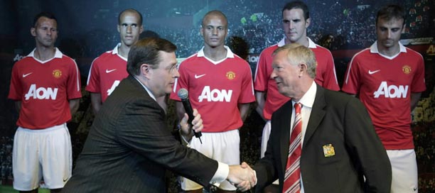 Aon CEO Greg Case shakes hands with Manchester United team manager Alex Ferguson after they unveiled the team's new uniform in Chicago. (AP)